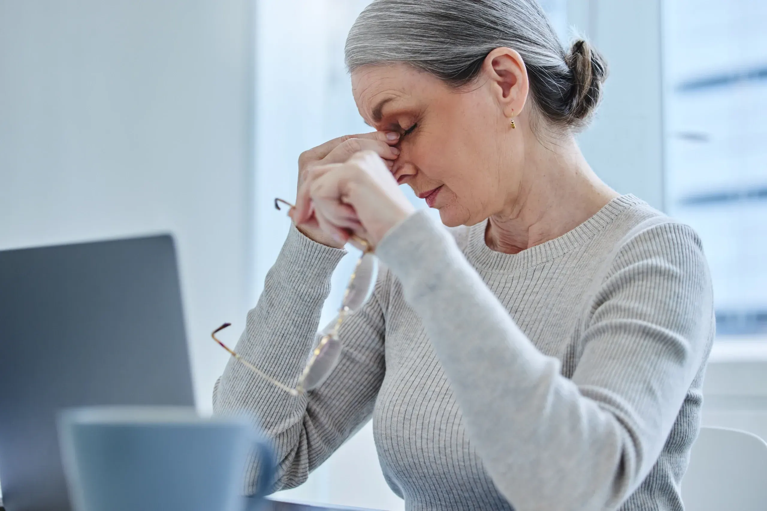 Woman pausing at her desk with tired eyes at Heritage Wellness Med Spa Crescent Springs
